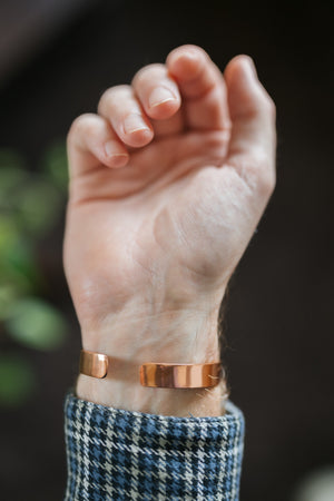 Kopero Pulseira de cobre Liso, no pulso, com a mão aberta e as pontas da pulseira visíveis