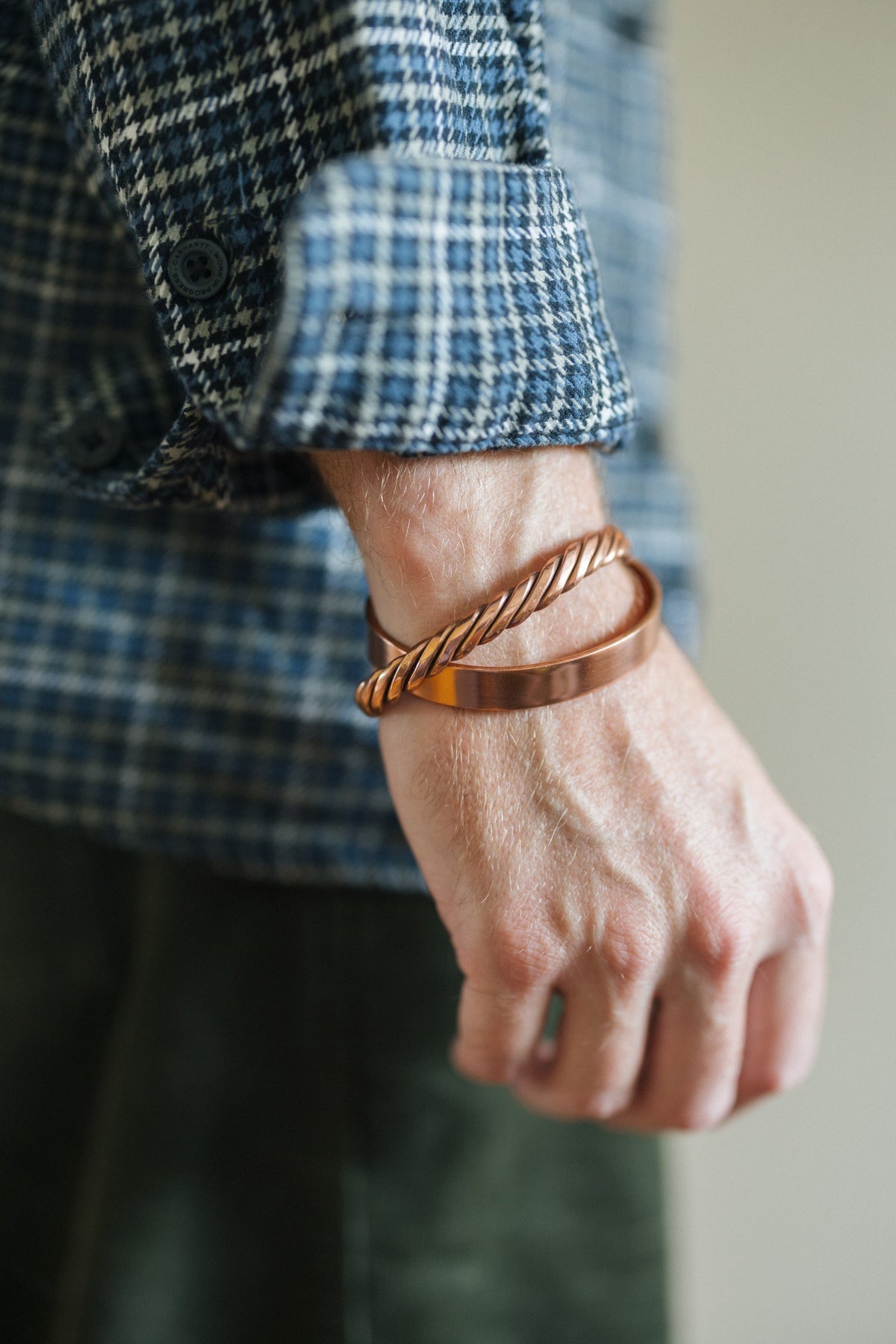 Kopero Pulseira de cobre Liso, no pulso sobre uma manga de camisa aos quadrados, juntamente com uma pulseira torcida