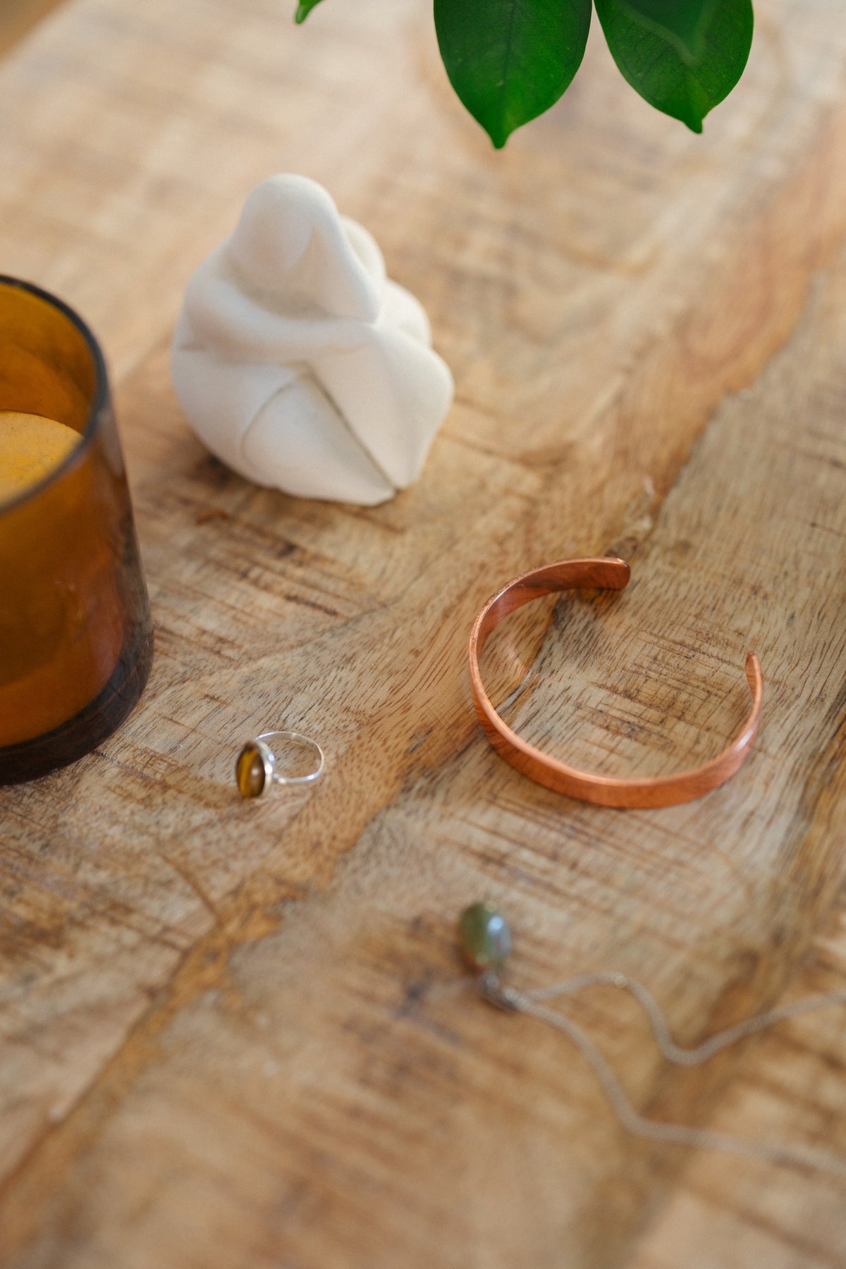 Kopero Pulseira de cobre Liso, sobre uma mesa de madeira ao lado de uma figura e de um anel