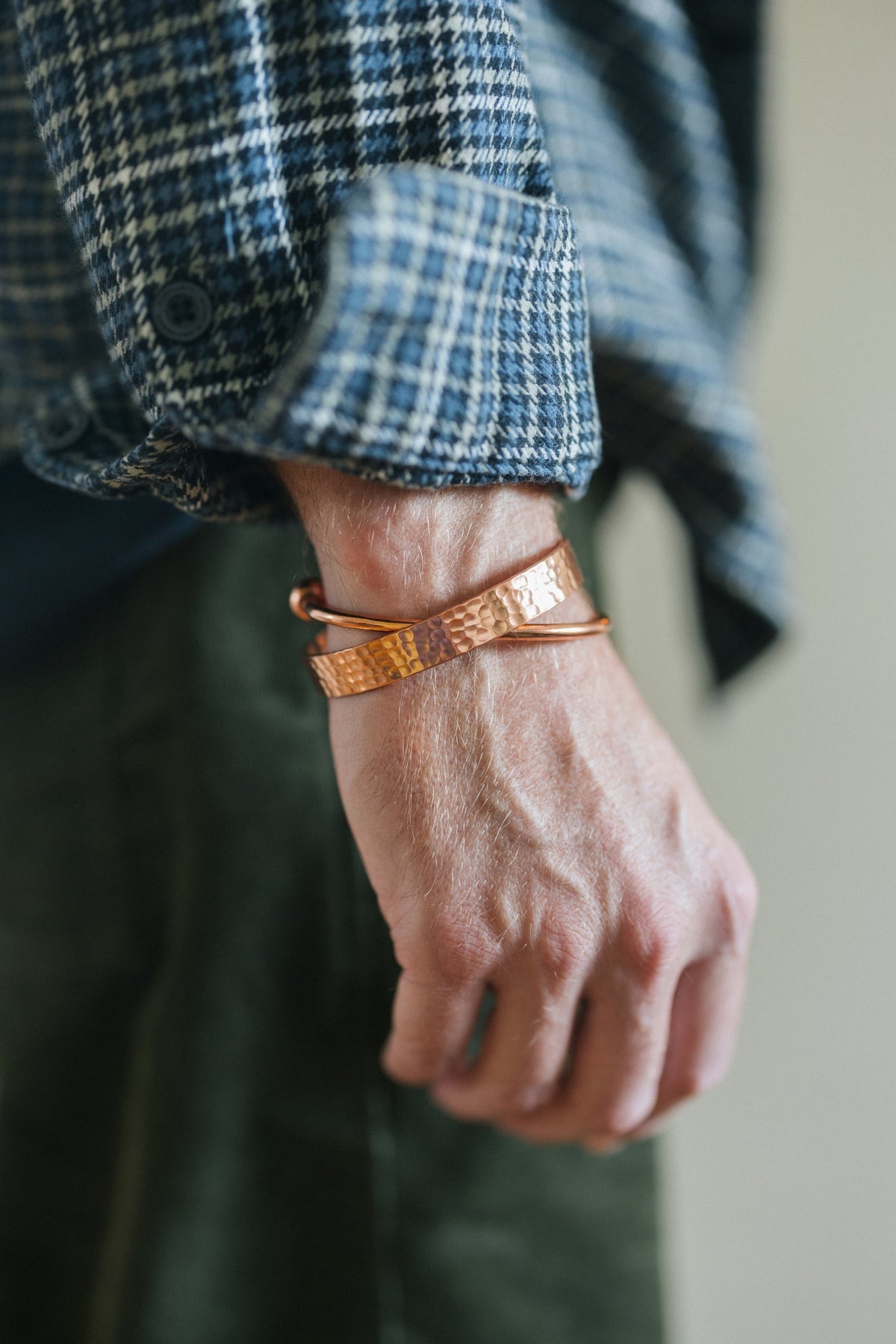 Kopero Pulseira de cobre Redondo, no pulso sobre uma manga de camisa aos quadrados, juntamente com uma pulseira martelada