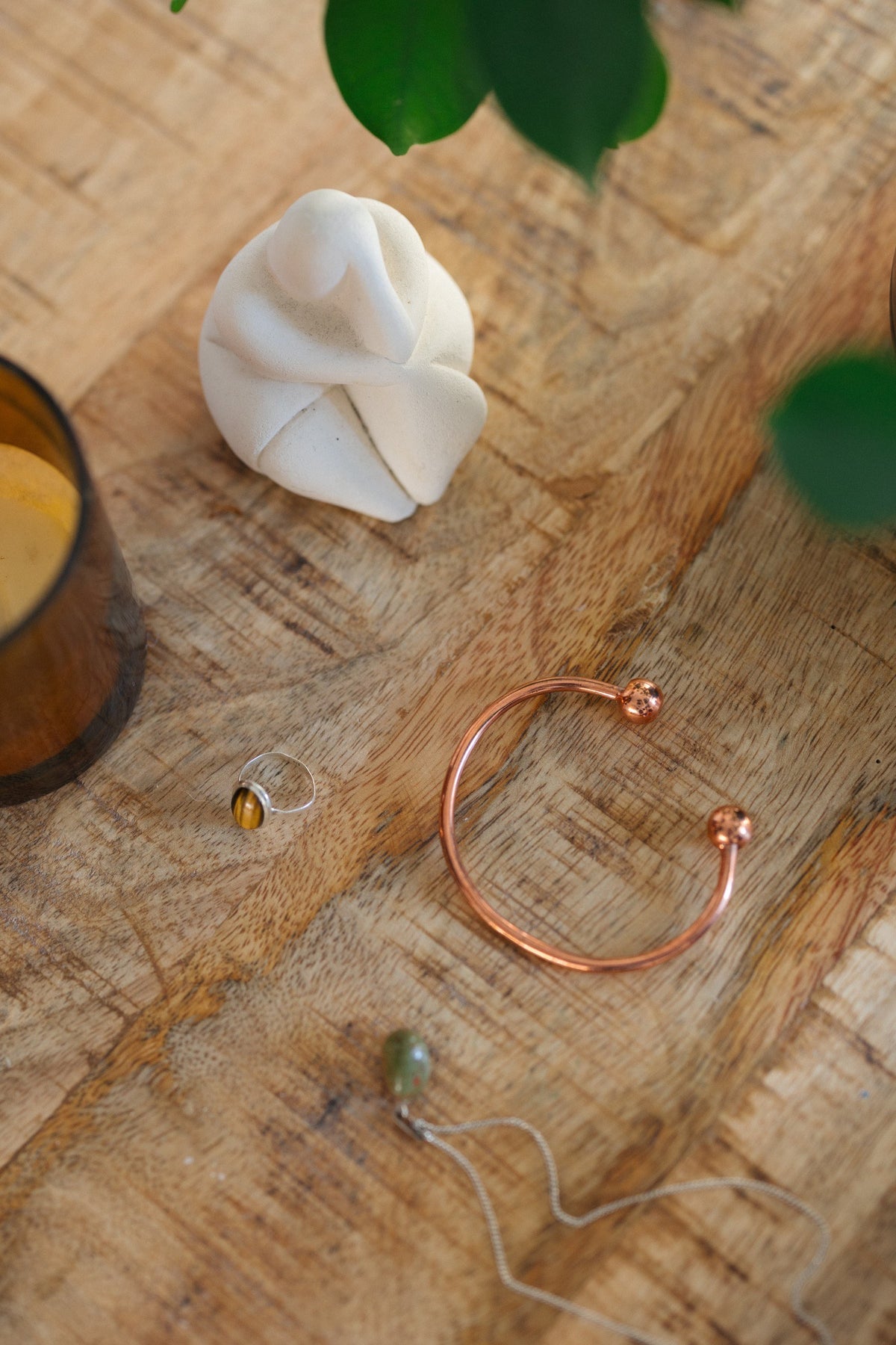 Kopero Pulseira de cobre Redondo, sobre uma mesa de madeira ao lado de uma figura e de um anel