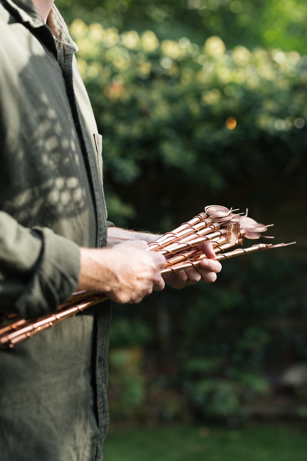 Kopero Eletrocultura, um molho de antenas de cobre em duas mãos no jardim