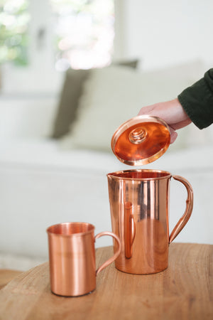 Kopero Jarro de cobre Liso, enquanto a tampa é levantada, com uma caneca ao lado