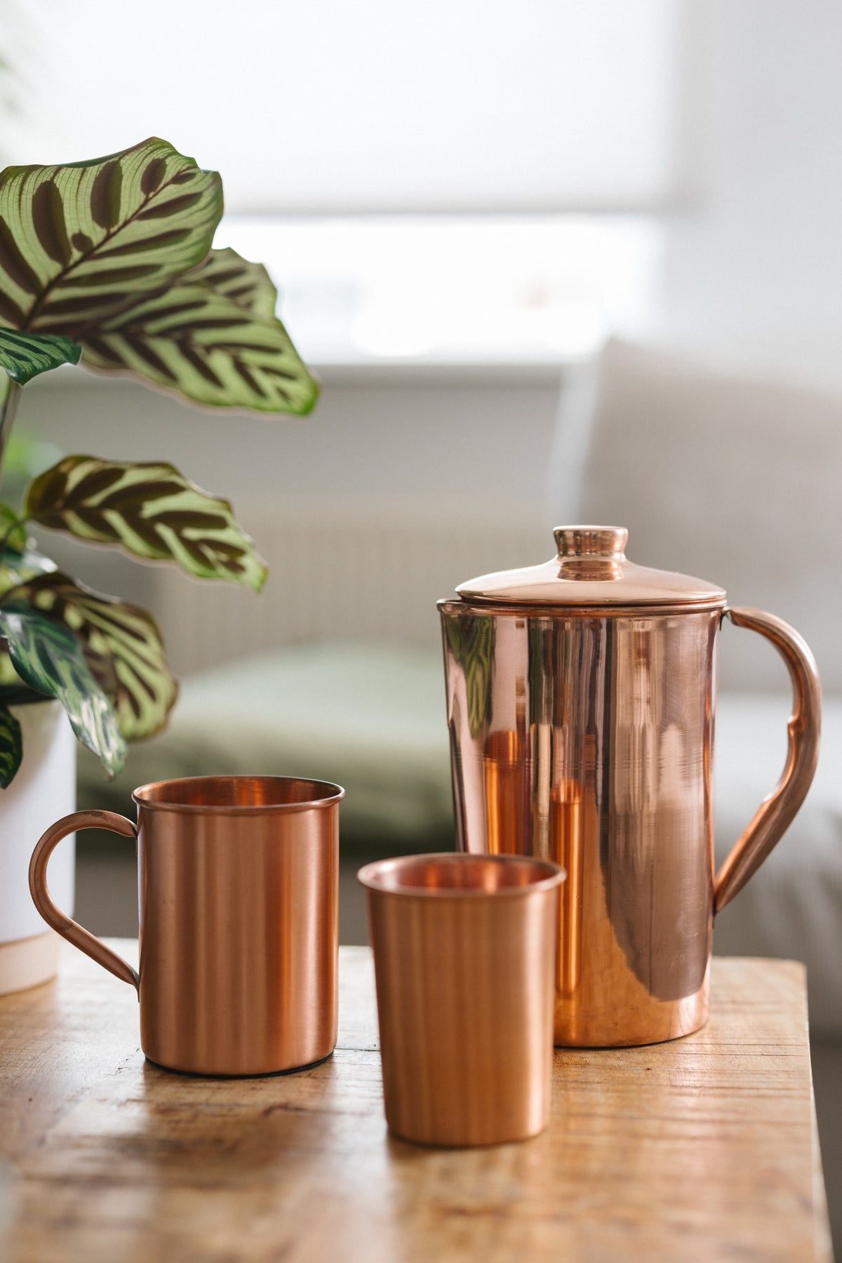Kopero Jarro de cobre Liso, com uma caneca e um copo sobre uma mesa de madeira
