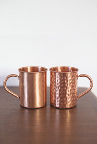 Kopero Caneca de Cobre, os dois acabamentos lado a lado sobre uma mesa de madeira