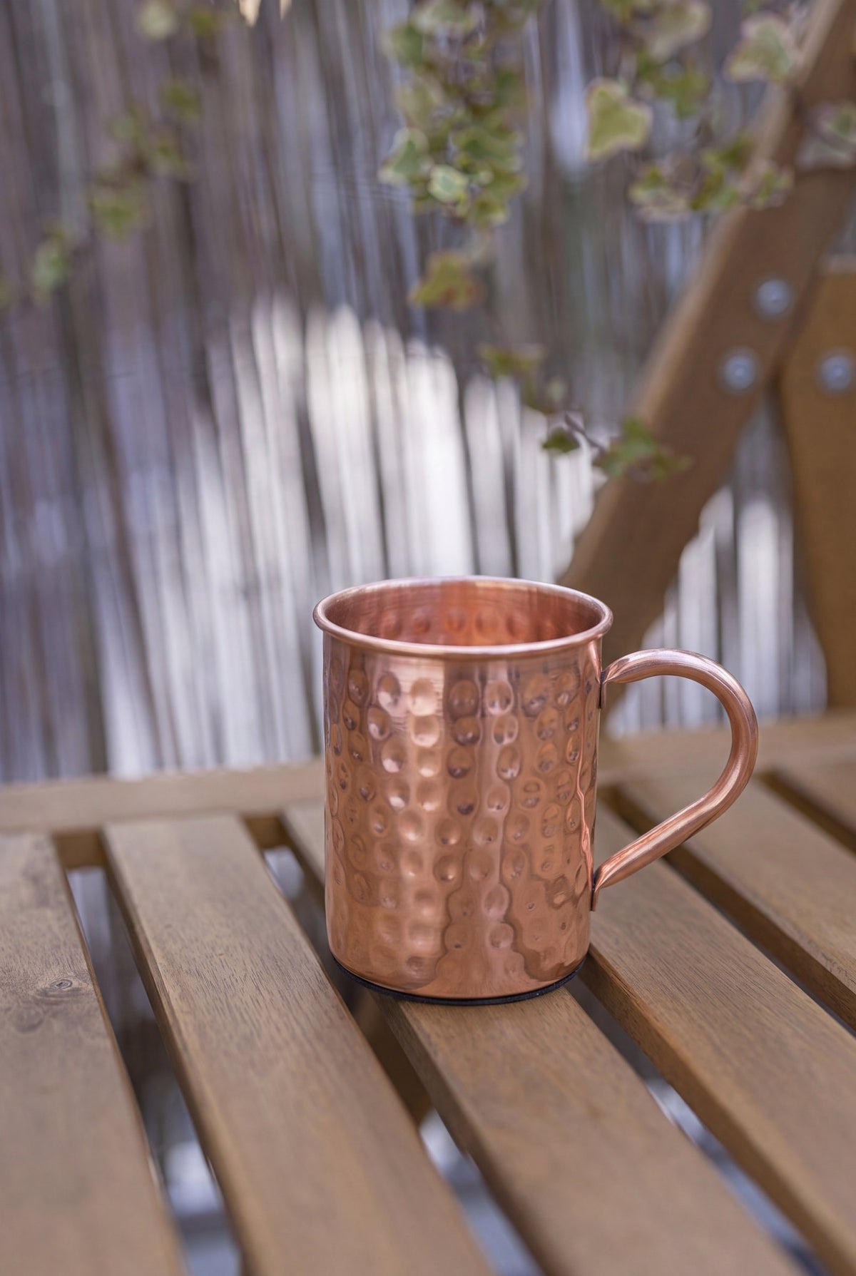 Kopero Caneca de Cobre Martelada de 400 ml sobre um banco de jardim de madeira