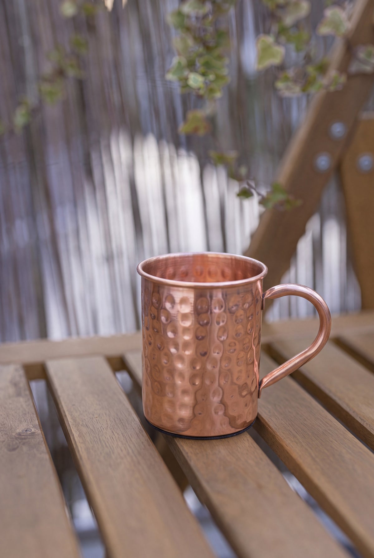 Caneca de cobre Kopero Premium Martelada, 400 ml, 100% cobre puro, ao ar livre numa mesa de jardim em madeira