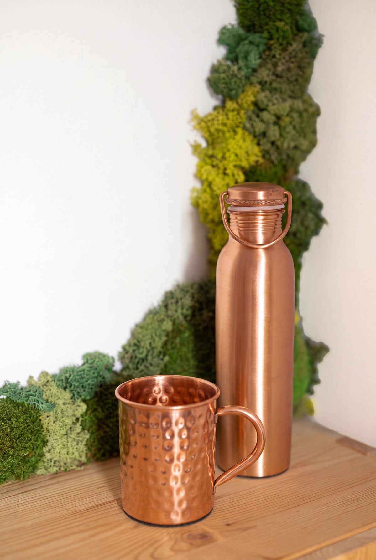 Caneca de cobre Kopero Premium Martelada junto a uma garrafa de cobre da coleção Kopero