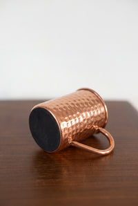 Caneca de cobre Kopero Premium Martelada deitada, com o fundo em feltro visível