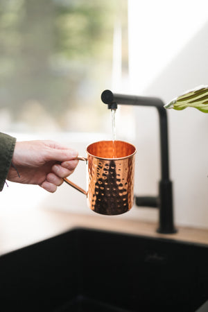 Kopero Caneca de cobre Martelado, numa mão debaixo da torneira