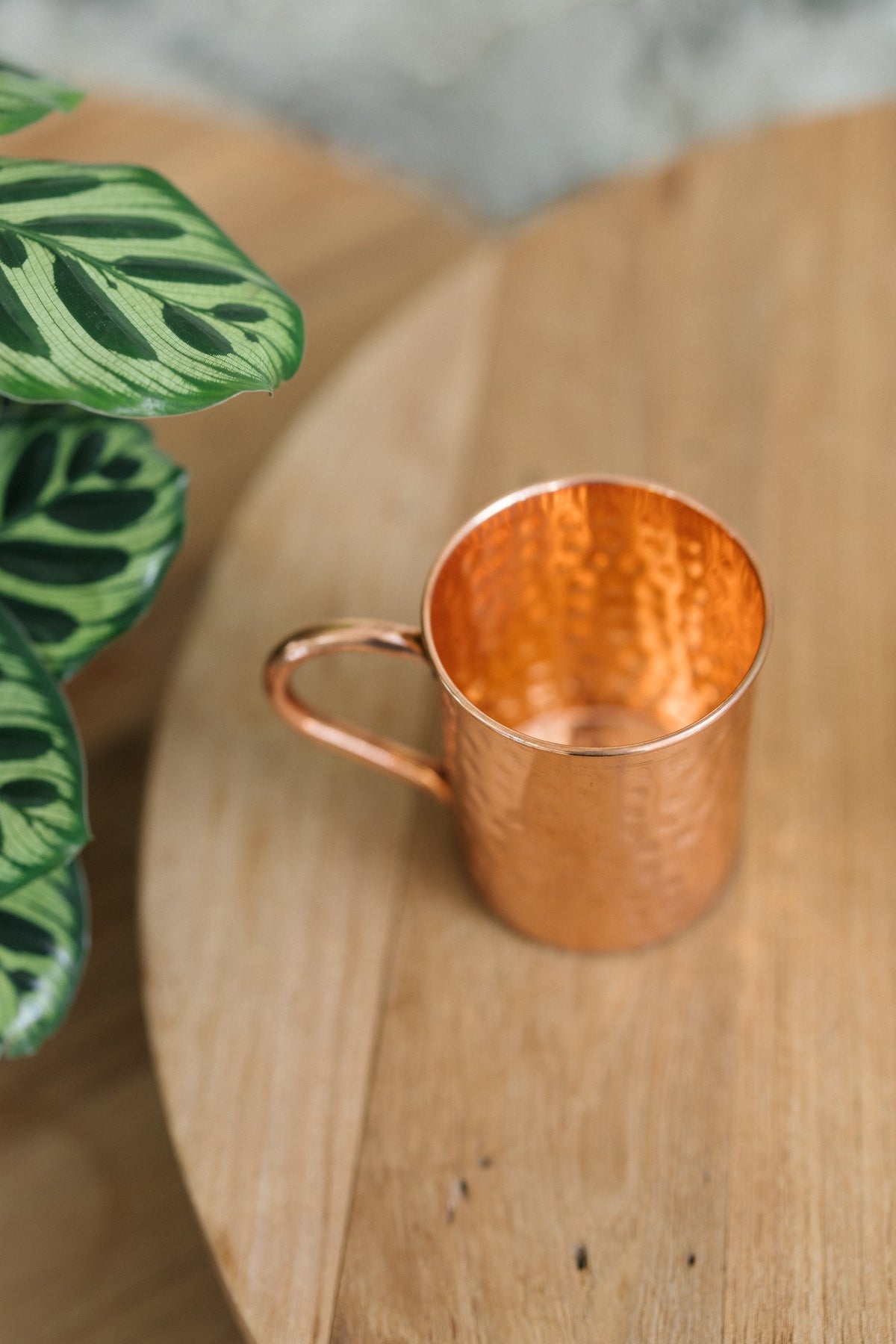 Kopero Caneca de cobre Martelado, deitada de lado sobre uma mesa redonda de madeira