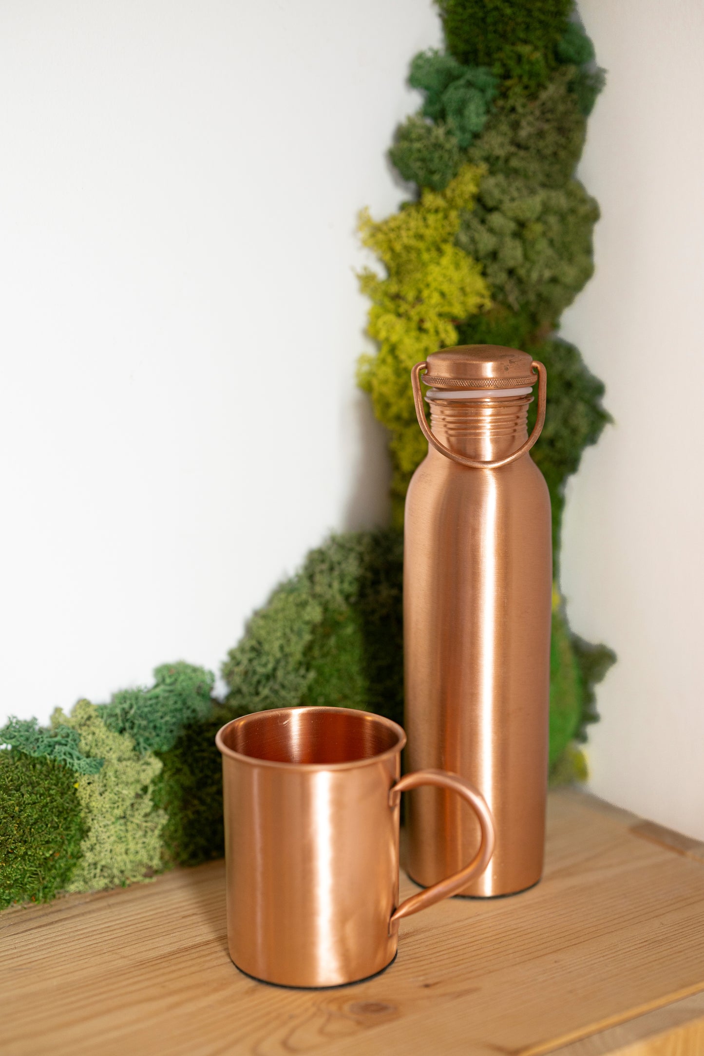 Caneca de cobre Kopero Premium Lisa junto a uma garrafa de cobre da coleção Kopero