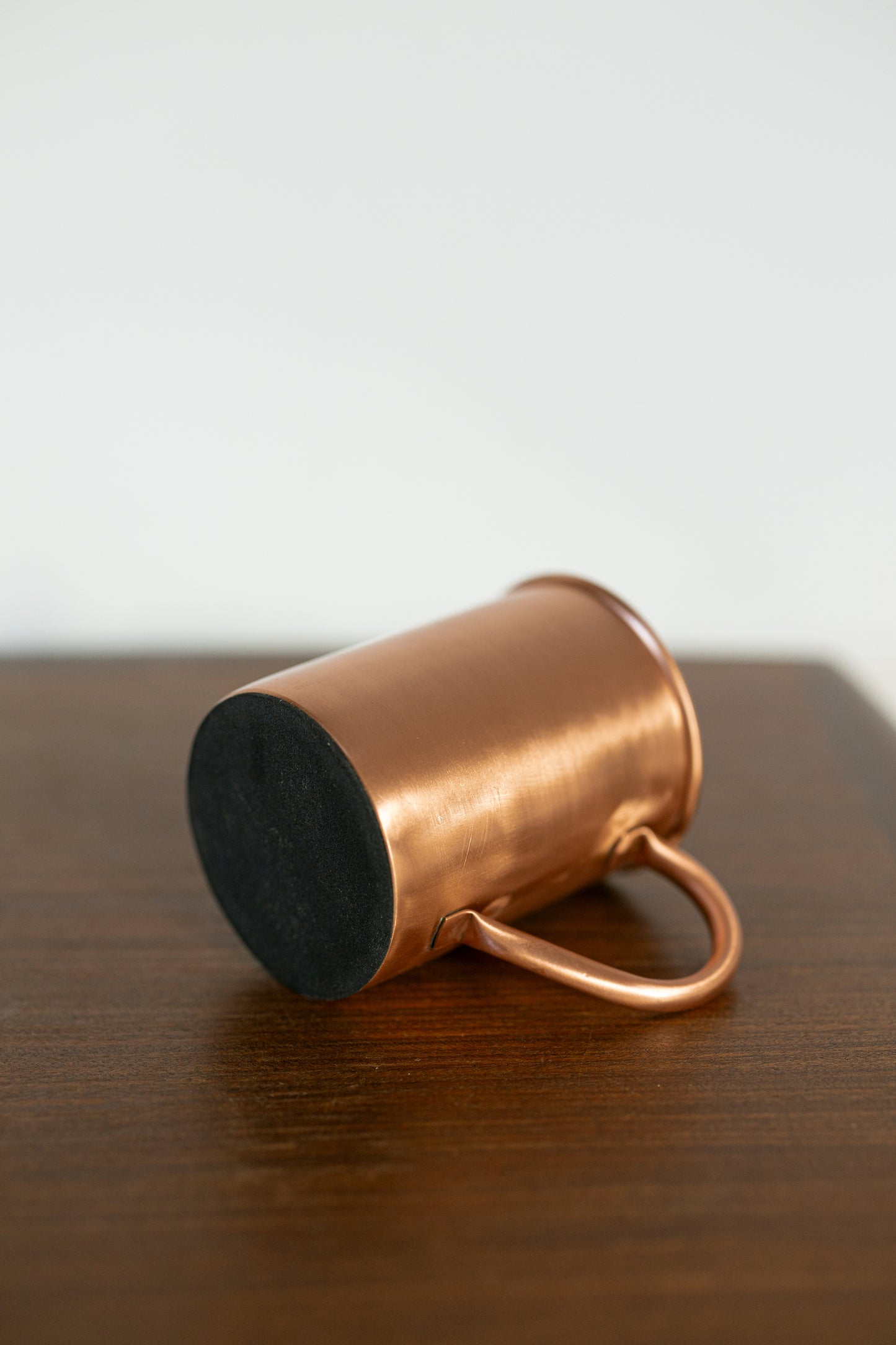 Caneca de cobre Kopero Premium Lisa deitada, com o fundo em feltro visível