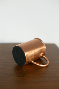 Caneca de cobre Kopero Premium Lisa deitada, com o fundo em feltro visível