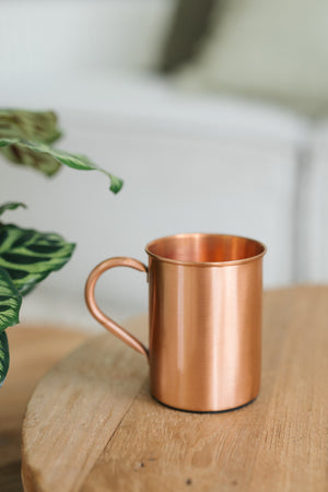 Kopero Caneca de cobre Liso, sobre uma mesa redonda de madeira em frente a um sofá