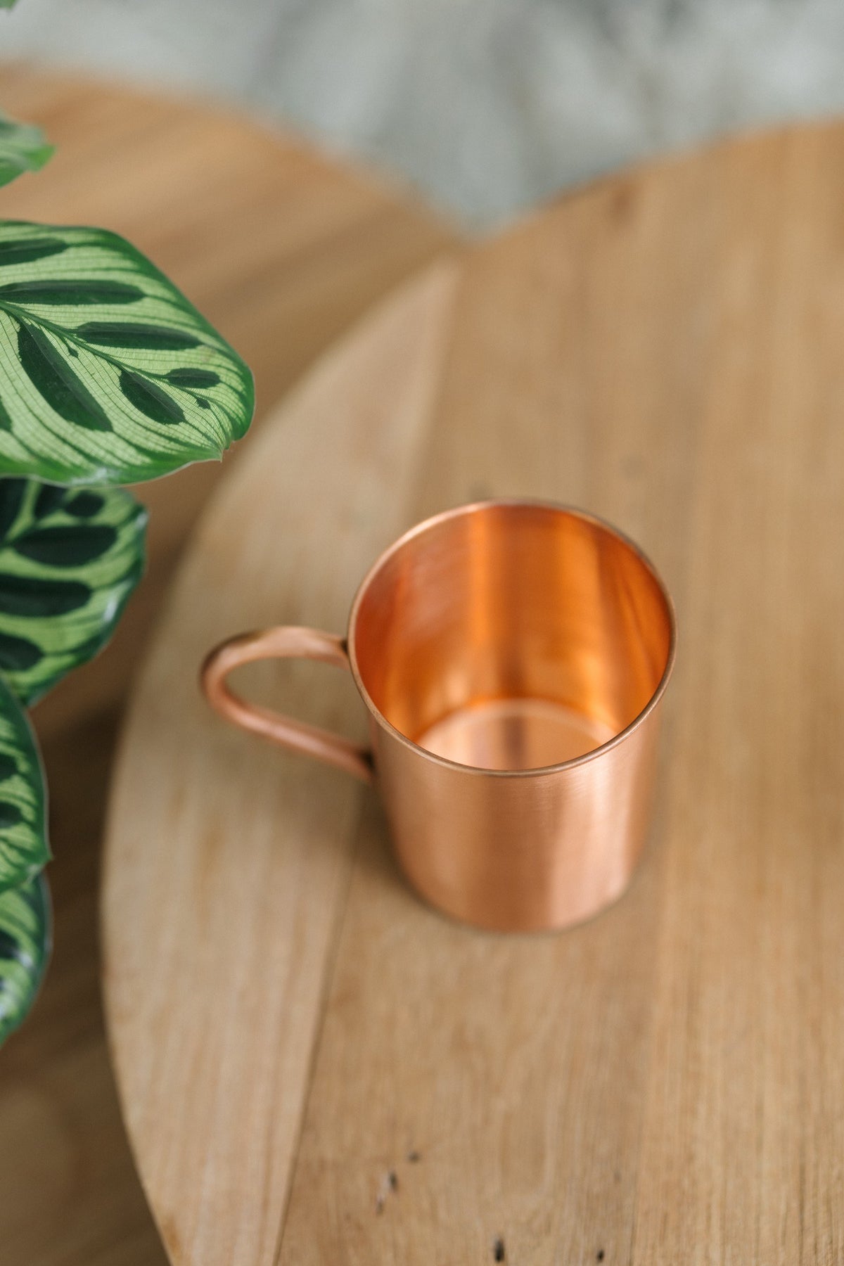 Kopero Caneca de cobre Liso, deitada de lado sobre uma mesa redonda de madeira